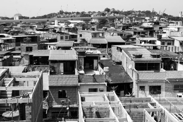 Vista aérea em preto e branco de um bairro urbano densamente povoado, com casas e telhados inacabados.