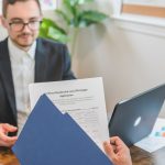 Corretor de financiamento conversa com cliente sobre uma solicitação de crédito imobiliário, com documentos sobre a mesa