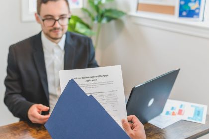 Corretor de financiamento conversa com cliente sobre uma solicitação de crédito imobiliário, com documentos sobre a mesa