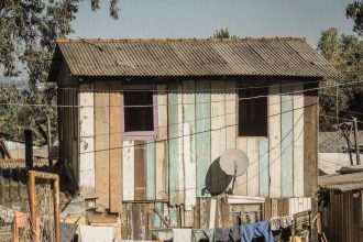 Casa de madeira em área rural, com roupas estendidas em um varal.